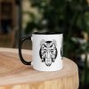 Afrocentric coffee mug featuring colorful African mask art with vibrant rim, handle, and interior