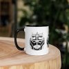 Ceramic afrocentric coffee mug featuring colorful African mask art with vibrant rim, handle, and interior