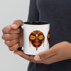 Orange and black African mask coffee mug with colorful rim, handle, and interior