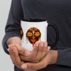 Orange and black African mask coffee mug with colorful rim, handle, and interior