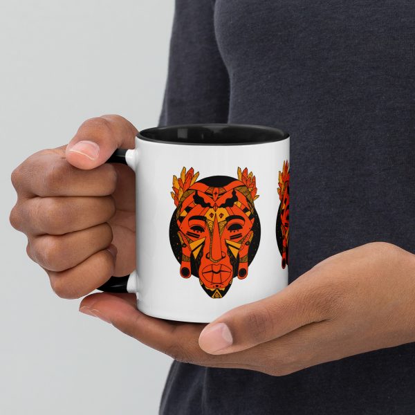 Orange and black African mask coffee mug with colorful rim, handle, and interior.