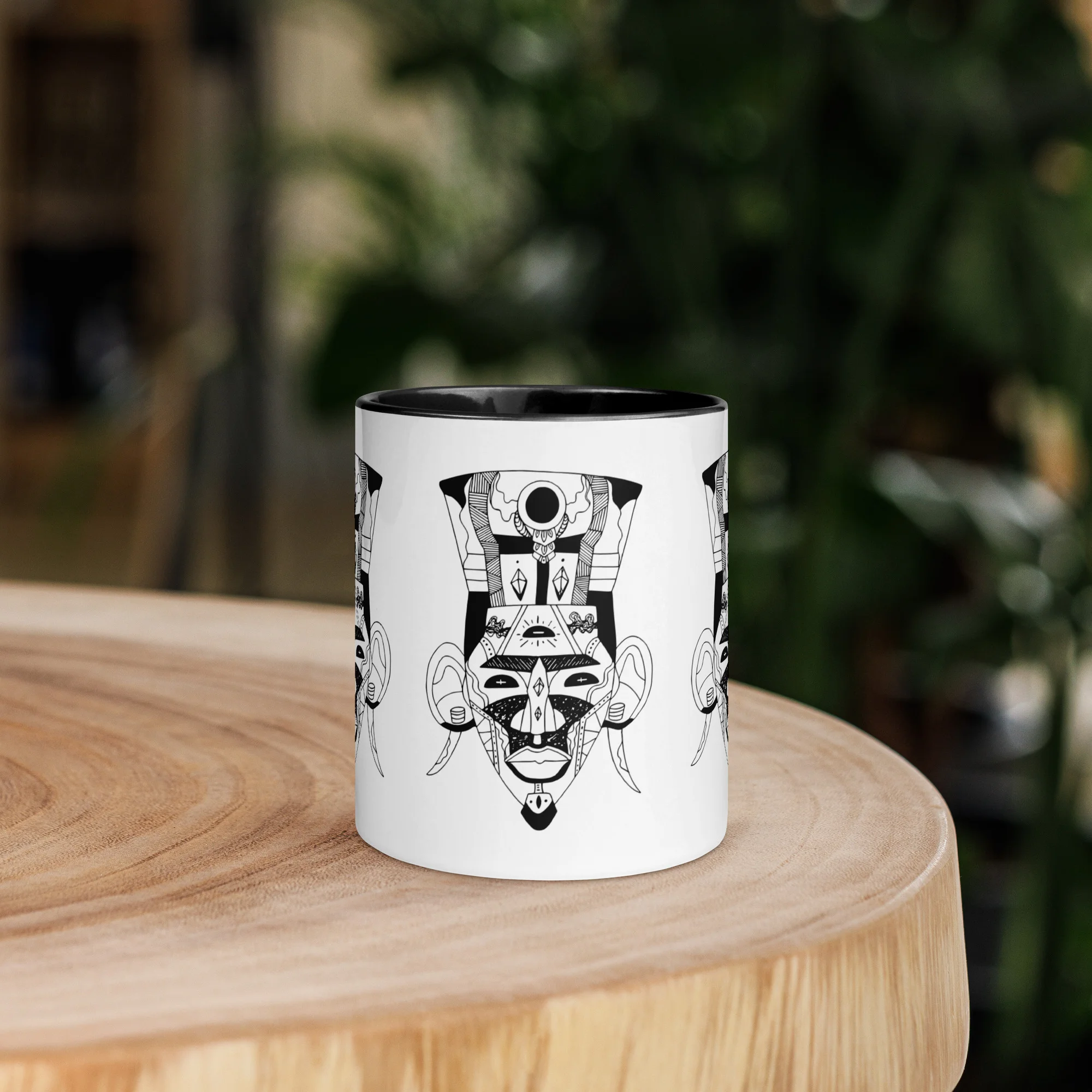 African mask art mug with black interior rim and geometric mask design on white ceramic.