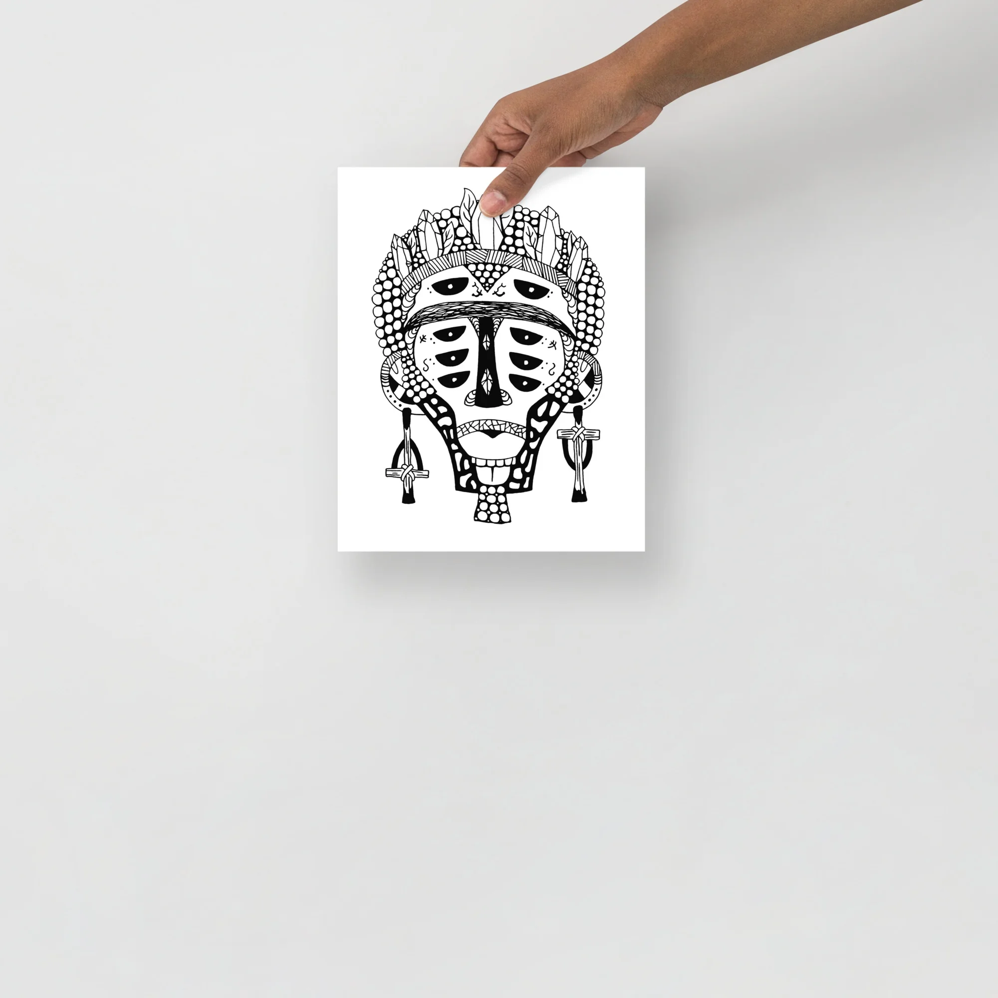 African mask art print featuring intricate black and white linework with geometric patterns and ornamental details on white paper.