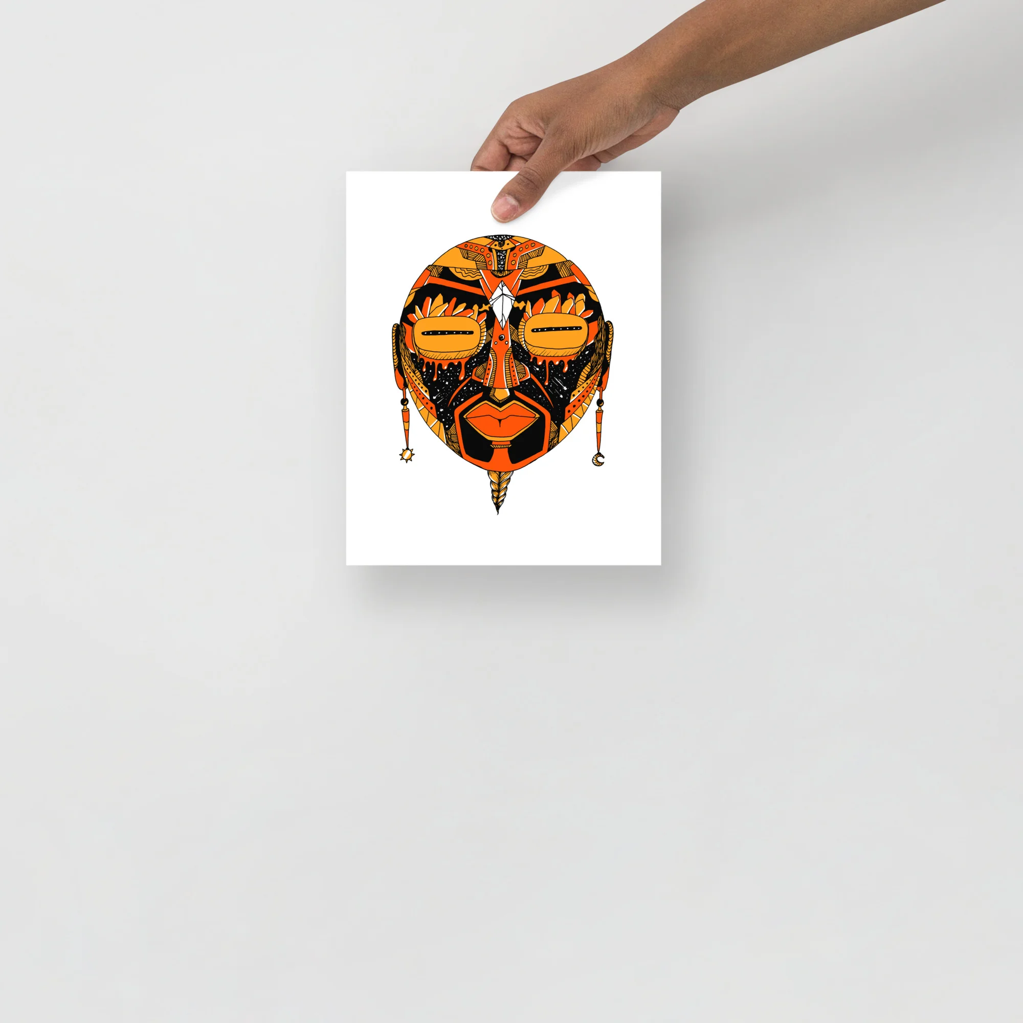 Striking orange and black African mask art print featuring geometric tribal design with bold line work and hanging beaded details.