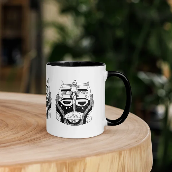 Afrocentric ceramic African mask mug with black handle on wooden table in garden setting