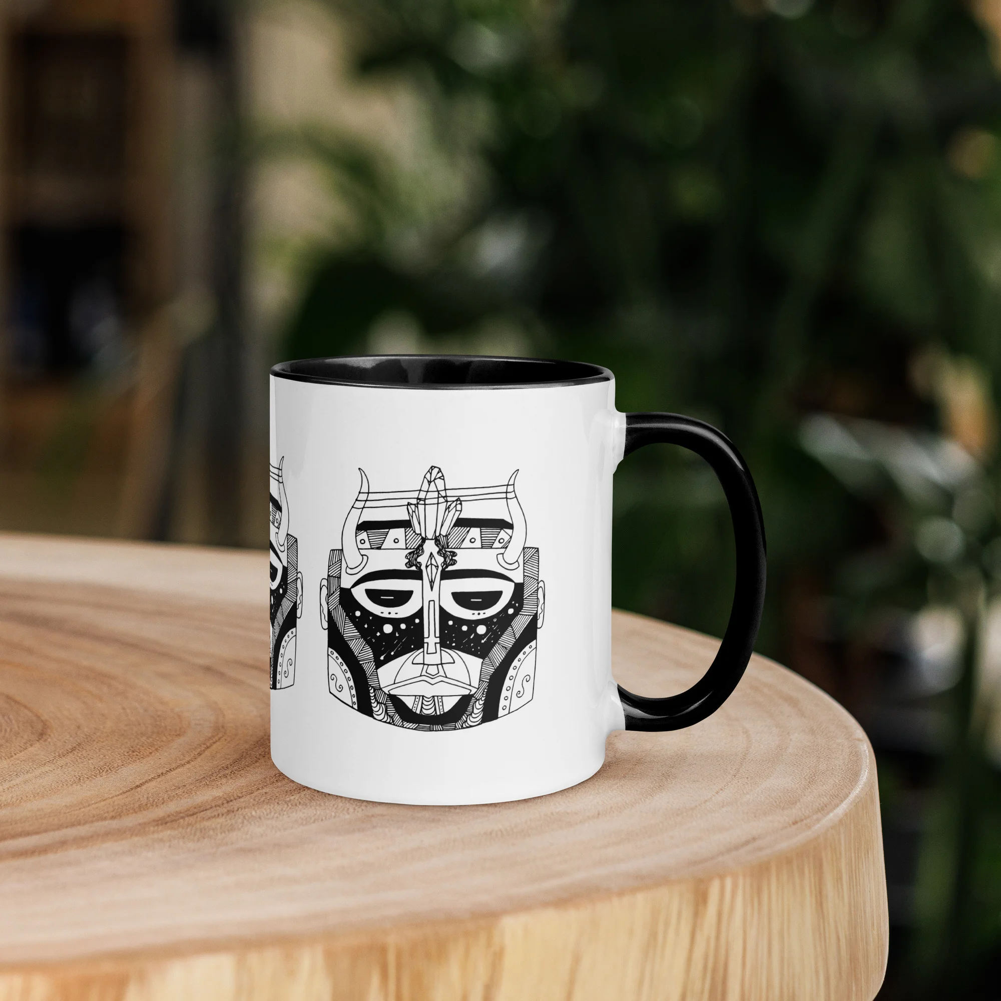 Afrocentric ceramic African mask mug with black handle on wooden table in garden setting