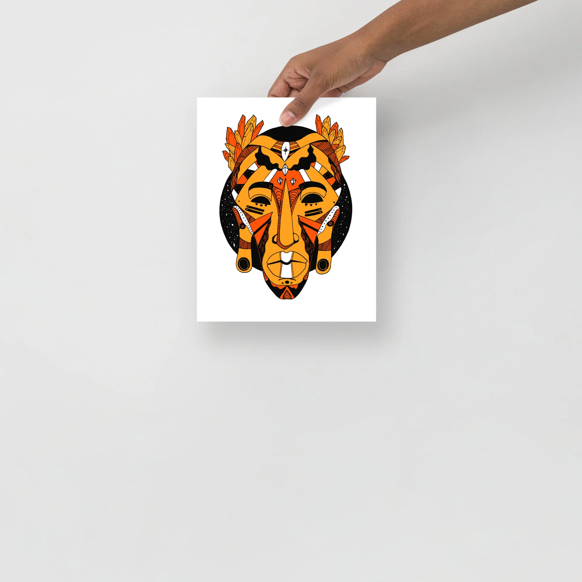 African mask wall art print featuring bold orange and black tribal design with feathered crown and geometric patterns
