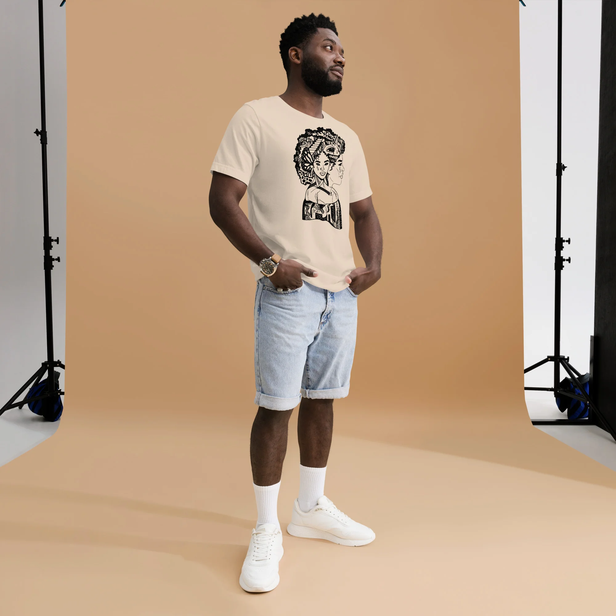 Man wearing cream afro woman t-shirt with black graphic design, paired with light blue denim shorts
