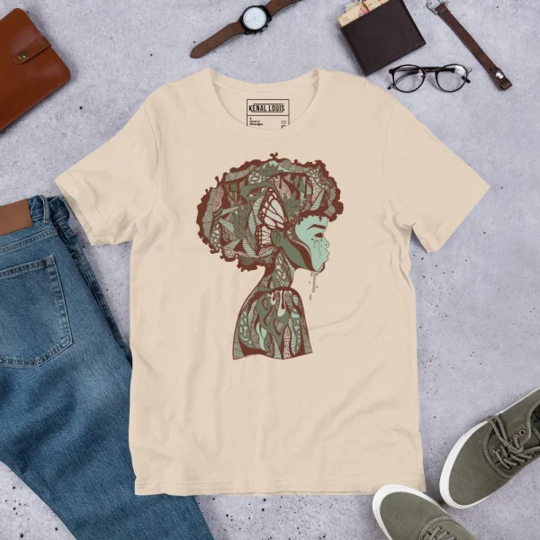 Cream-colored afrocentric art t-shirt featuring an ornate profile silhouette with intricate patterning in sage green and brown tones.