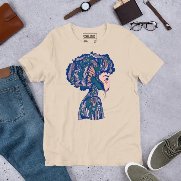 Cream afrocentric art t-shirt featuring a blue and pink profile silhouette with intricate patterned details, displayed flat lay with accessories.
