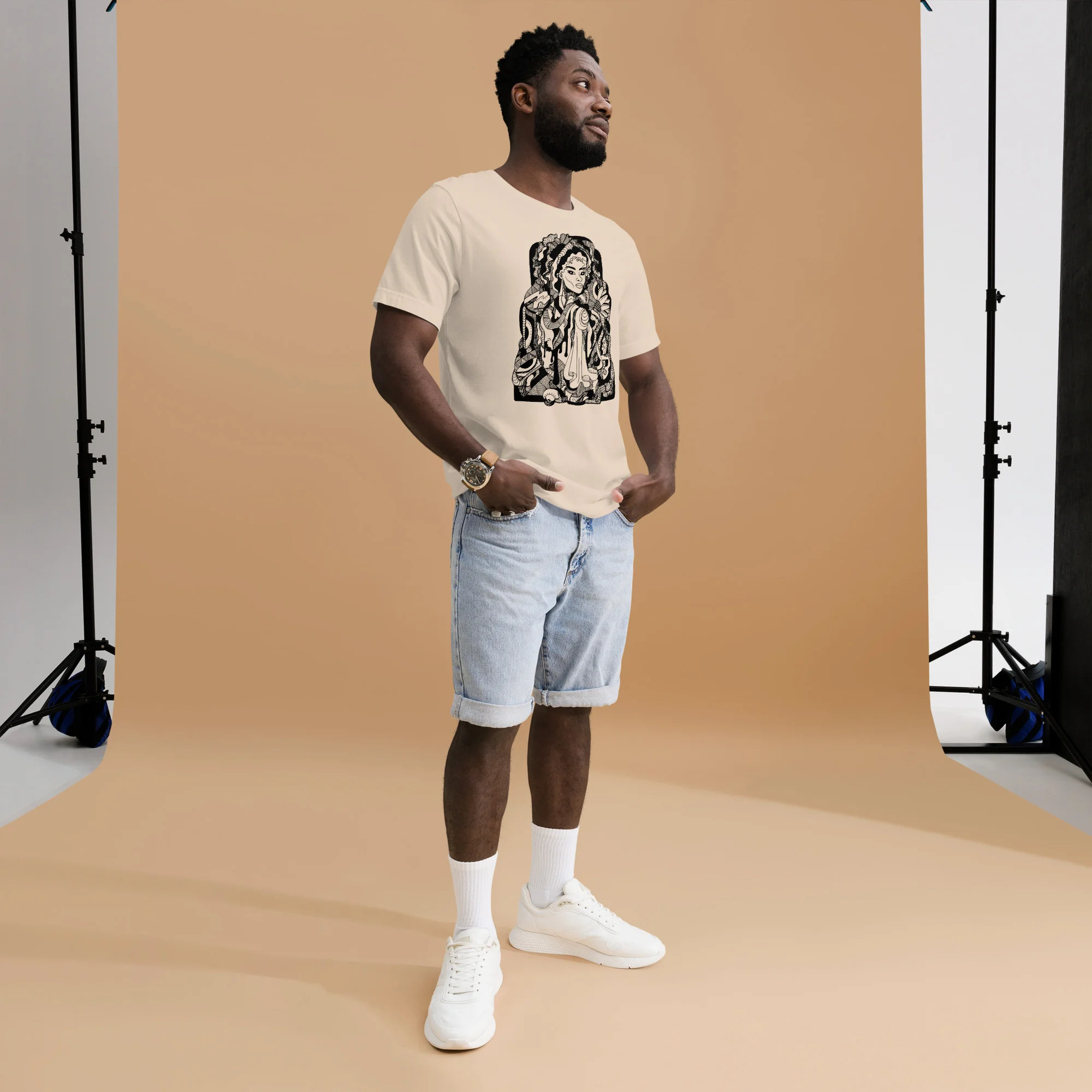 Man wearing cream afrocentric t-shirt with black culture portrait artwork, paired with light denim shorts