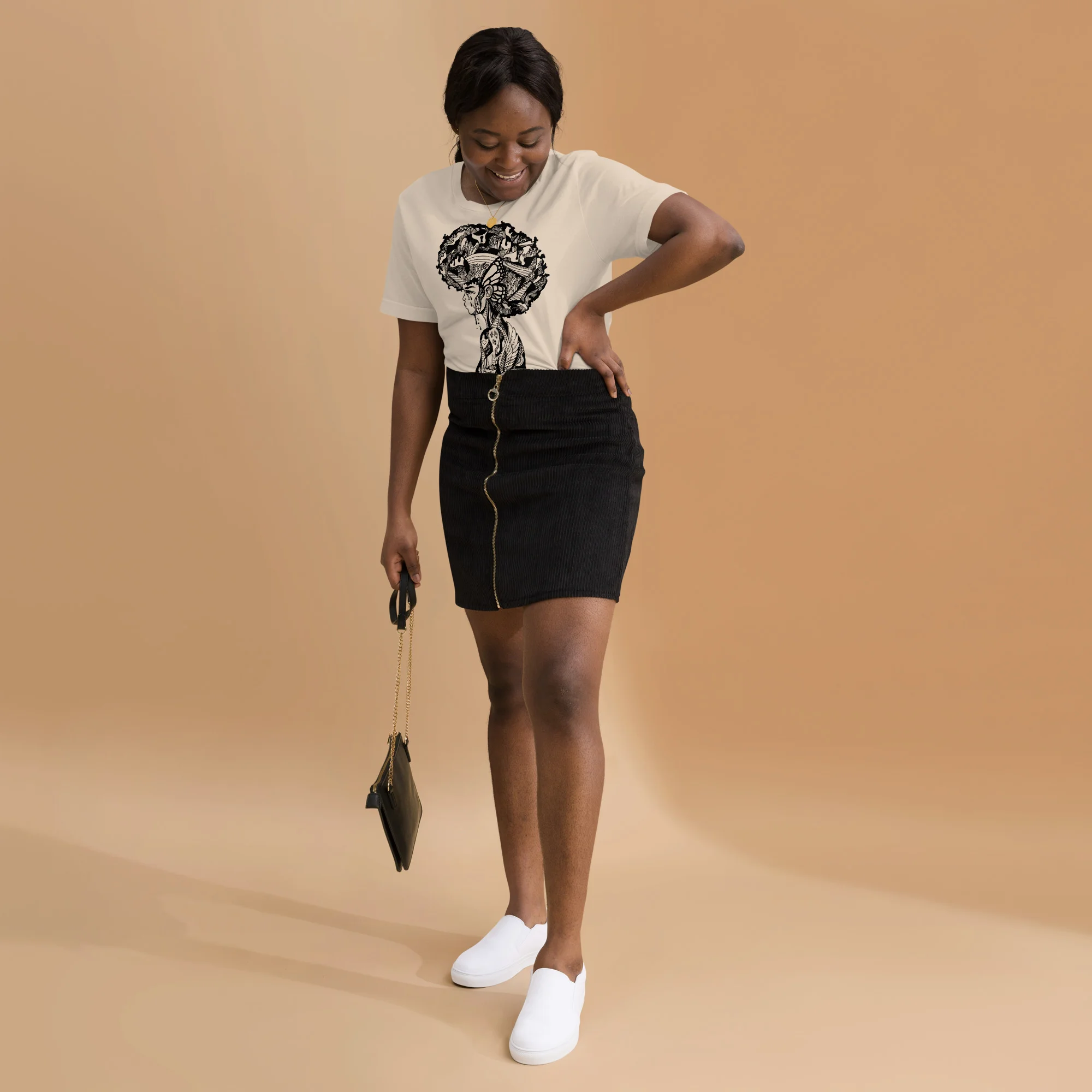 Woman wearing cream afrocentric t-shirt with Her Beautiful Mind graphic design and black skirt