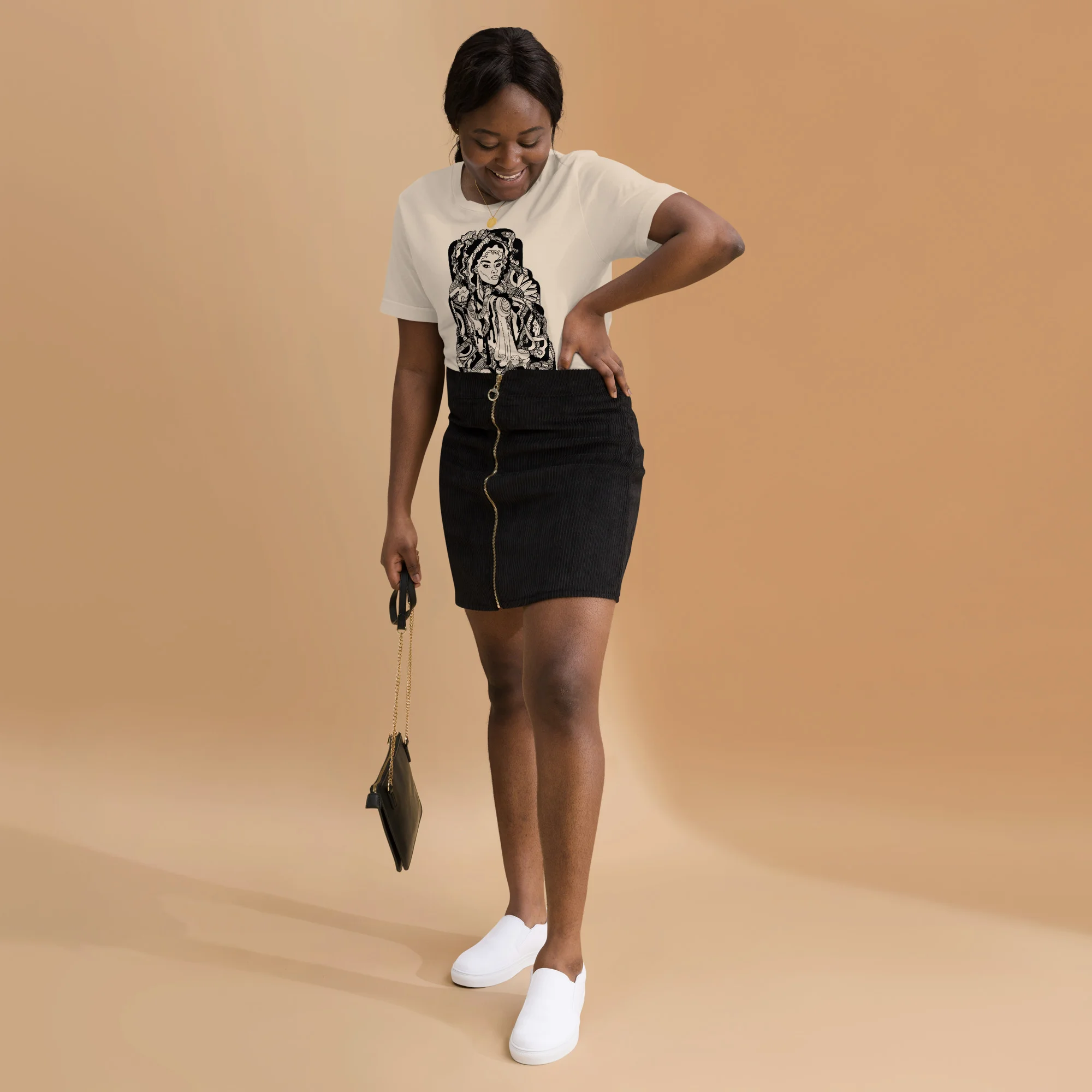 Woman wearing cream afrocentric t-shirt with black mirage culture graphic, styled with black skirt and white sneakers