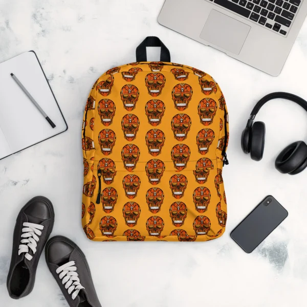 Orange day of the dead skull backpack with colorful sugar skull pattern displayed flat lay with laptop and accessories