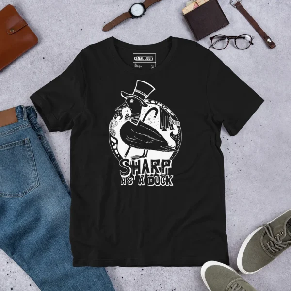 Black duck t-shirt with white line art graphic featuring a sophisticated duck wearing a top hat, styled flat lay with accessories