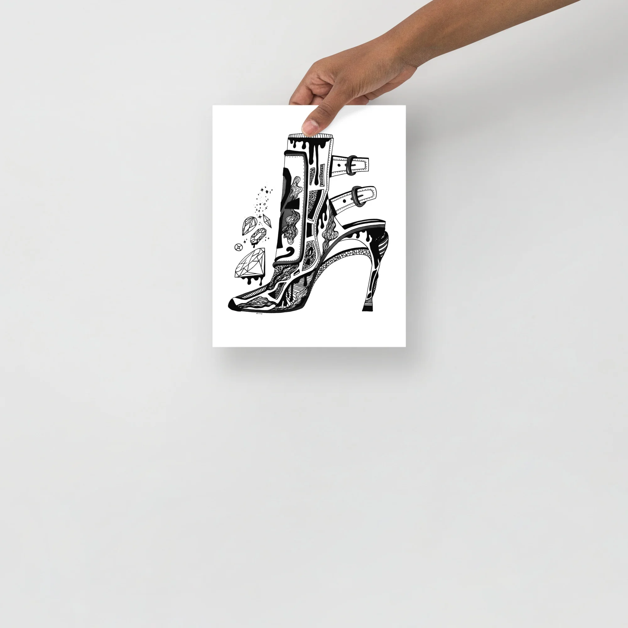 Hand holding high heels and diamonds art print showcasing intricate black ink illustration on white paper