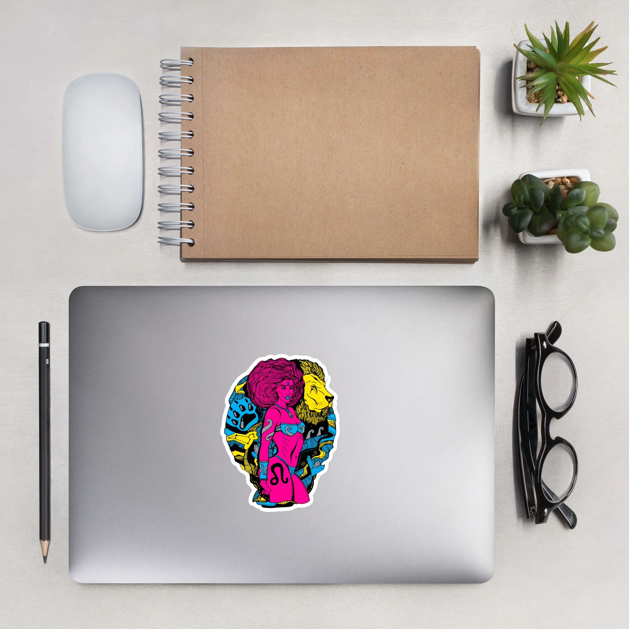 Colorful leo sticker with CMYK zodiac warrior art applied to silver laptop in workspace setup