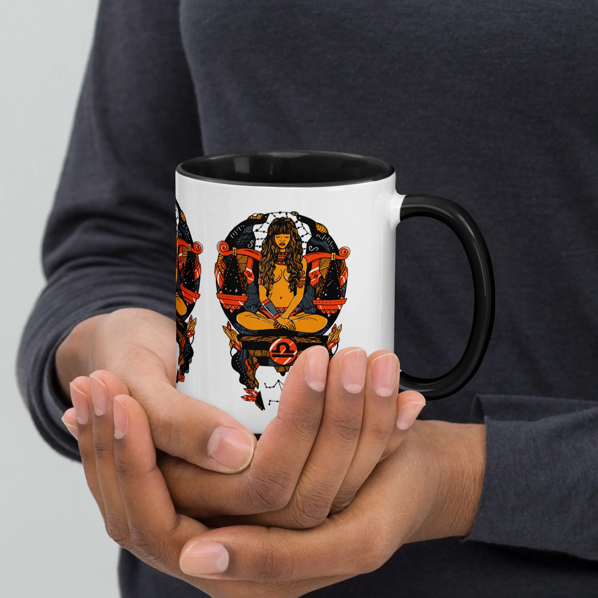 Libra zodiac coffee mug with orange and black artwork held in hands, featuring astrological design by Kenal Louis