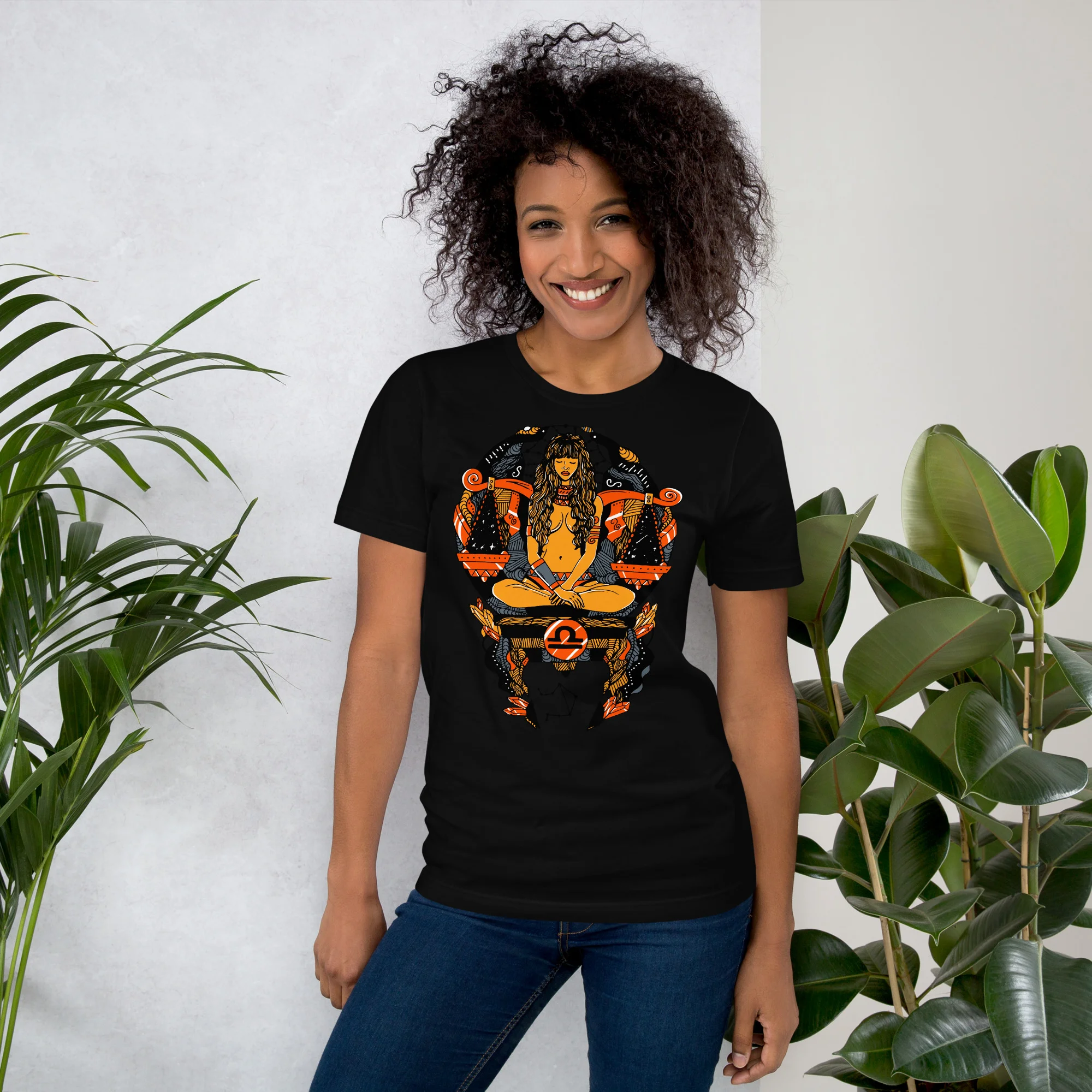 Woman wearing black libra zodiac t-shirt with orange graphic design and blue jeans