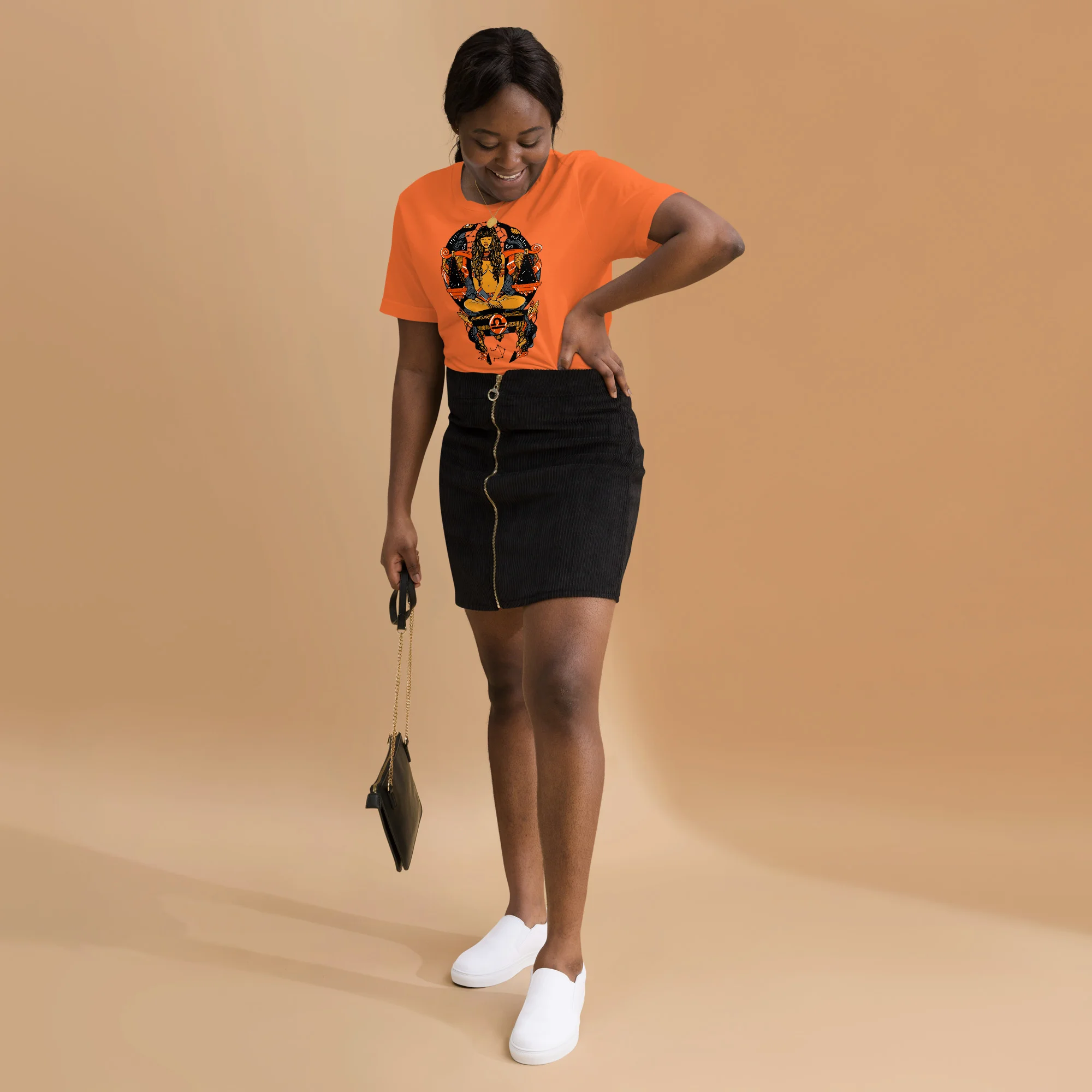 Woman wearing orange libra zodiac t-shirt with black graphic design and black mini skirt