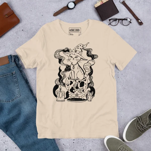 Cream unisex magical cat t-shirt featuring black line art illustration of a fortune cat with mystical elements and decorative details