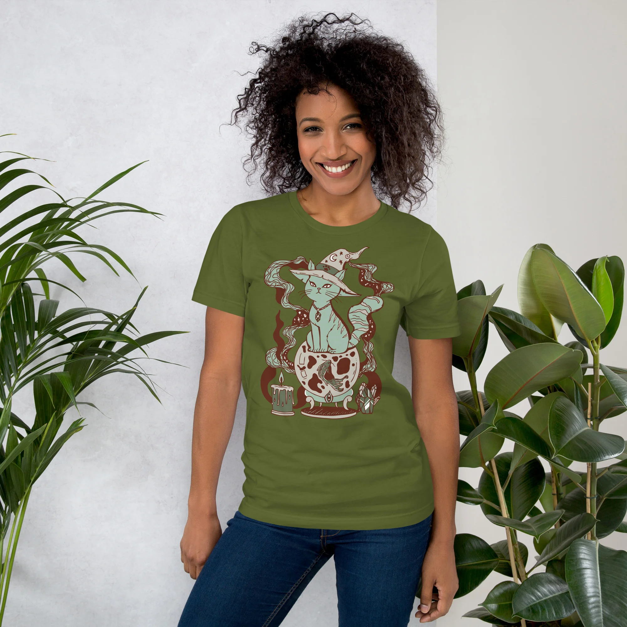 Woman wearing a sage green magical cat t-shirt with whimsical fortune design and red accents