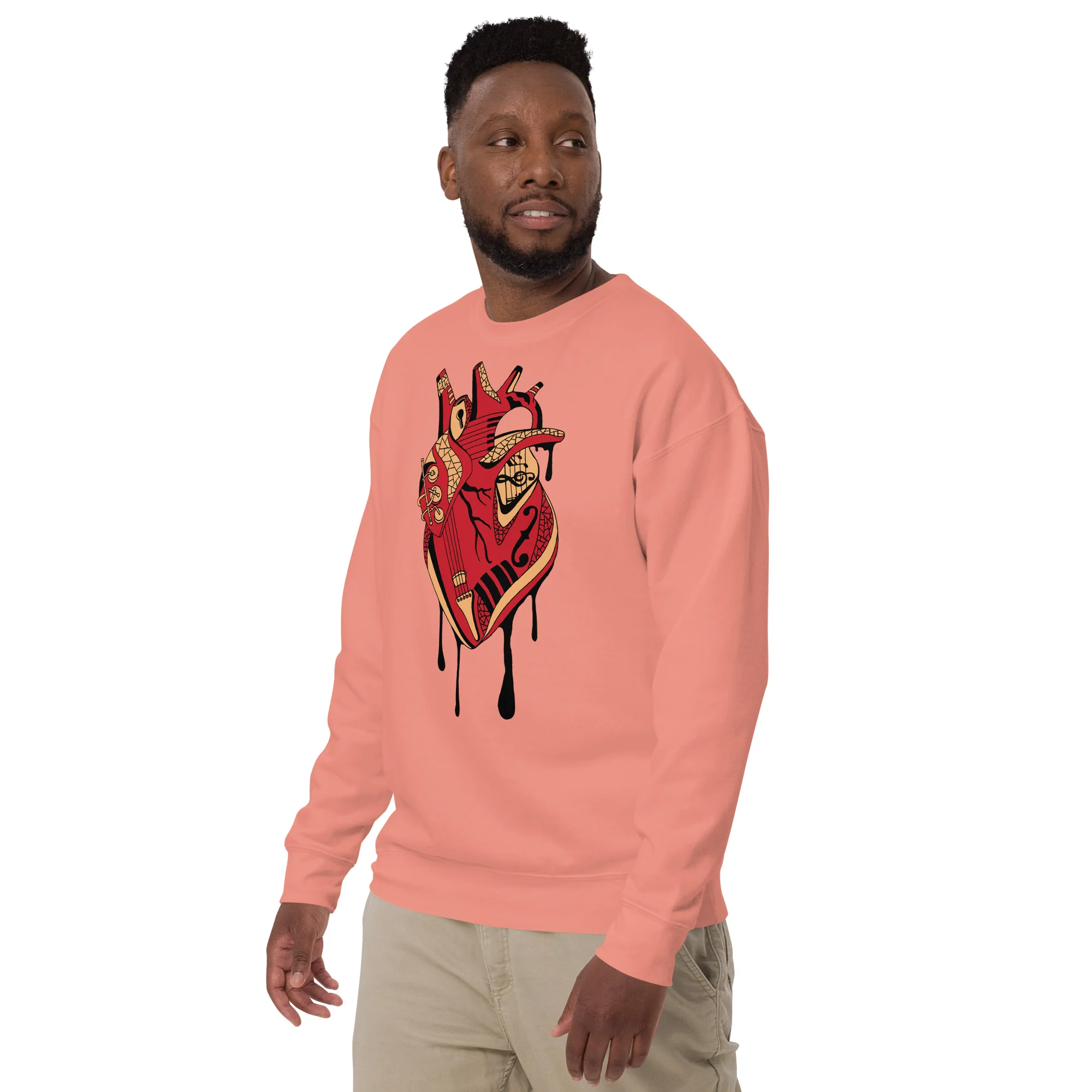 Man wearing dusty rose musical heart sweatshirt with red and cream anatomical heart design featuring musical instruments