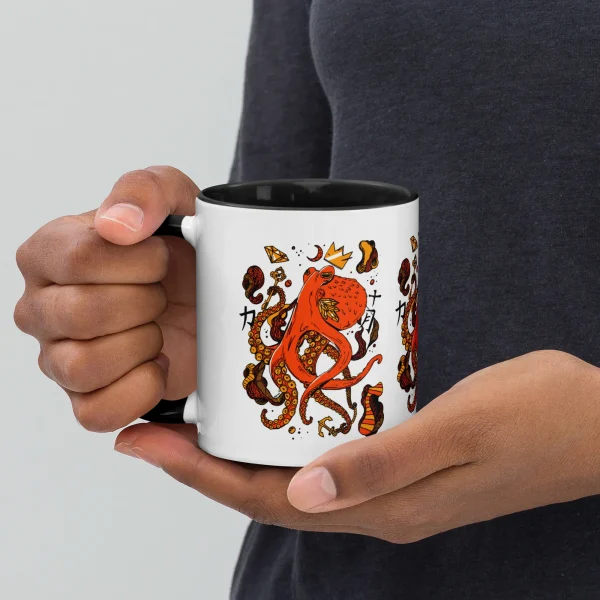 Person holding white octopus mug with orange and black mystical ocean art design and black interior rim