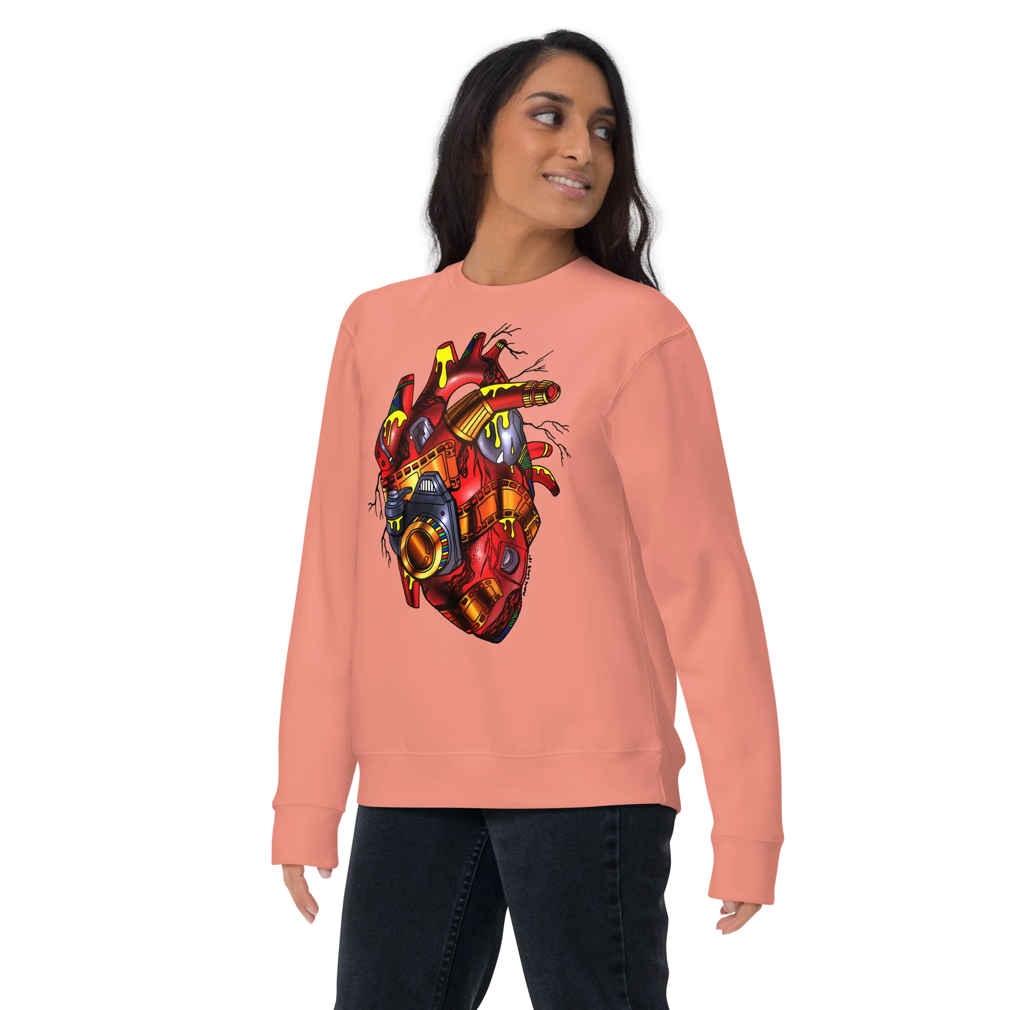 Woman wearing a salmon pink photographer sweatshirt with a red and gold mechanical heart design featuring camera elements