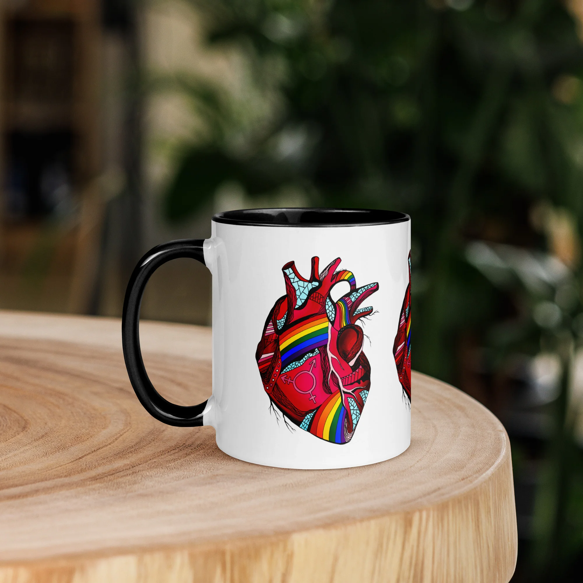 Pride heart mug with colorful rainbow design and black ceramic rim on wooden surface