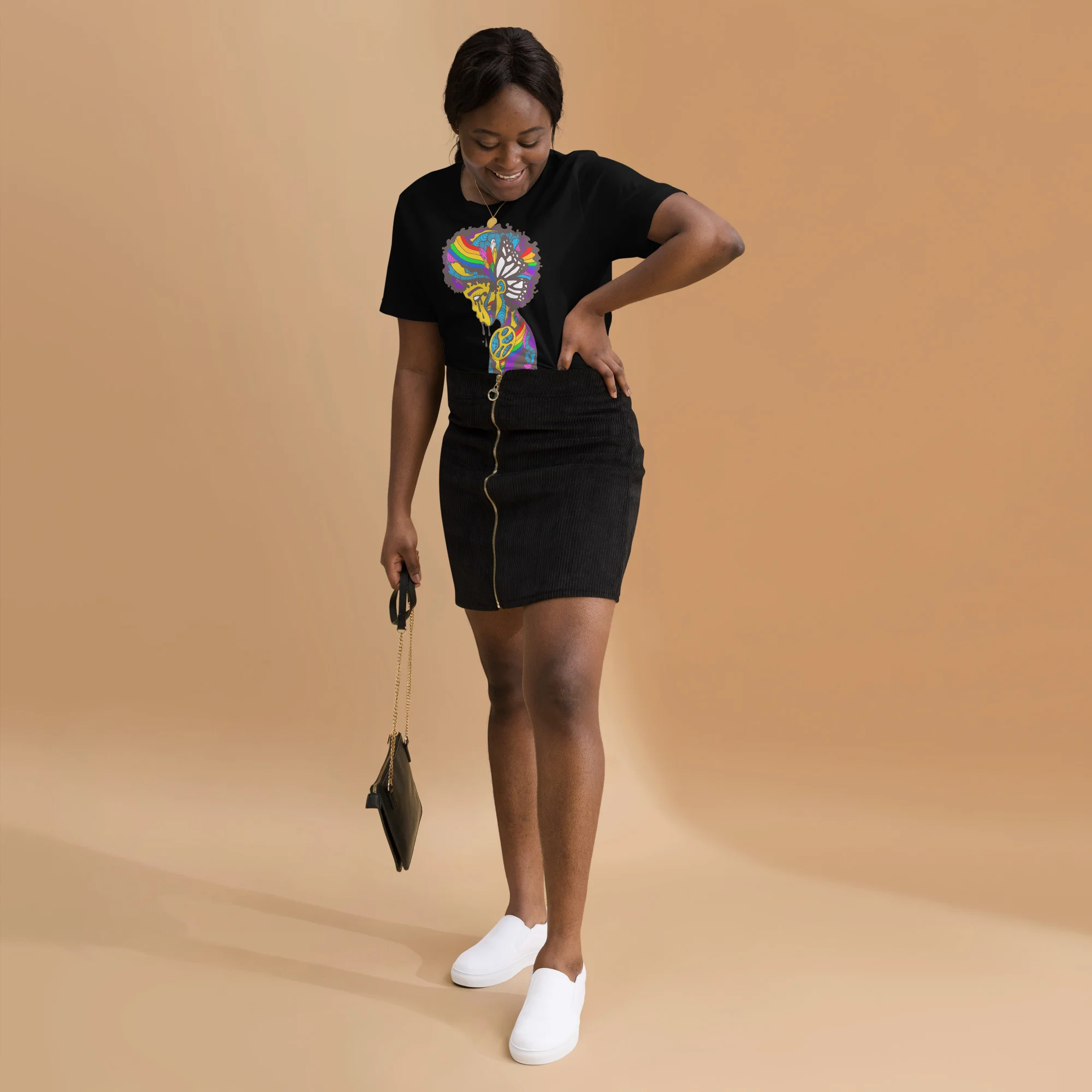 Woman wearing black pride t-shirt with colorful rainbow butterfly design, styled with black skirt and white sneakers