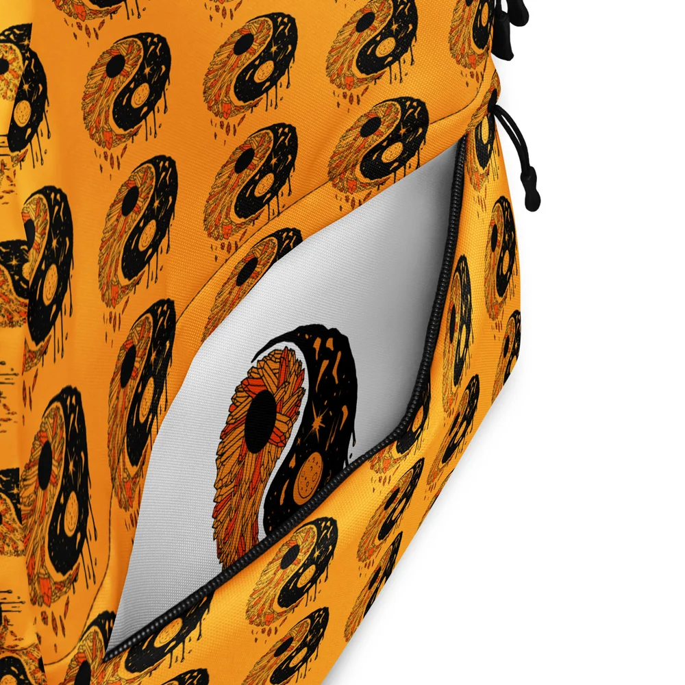 Orange and black yin yang backpack displayed at an angle showing the repeating eye pattern and side zipper pocket detail