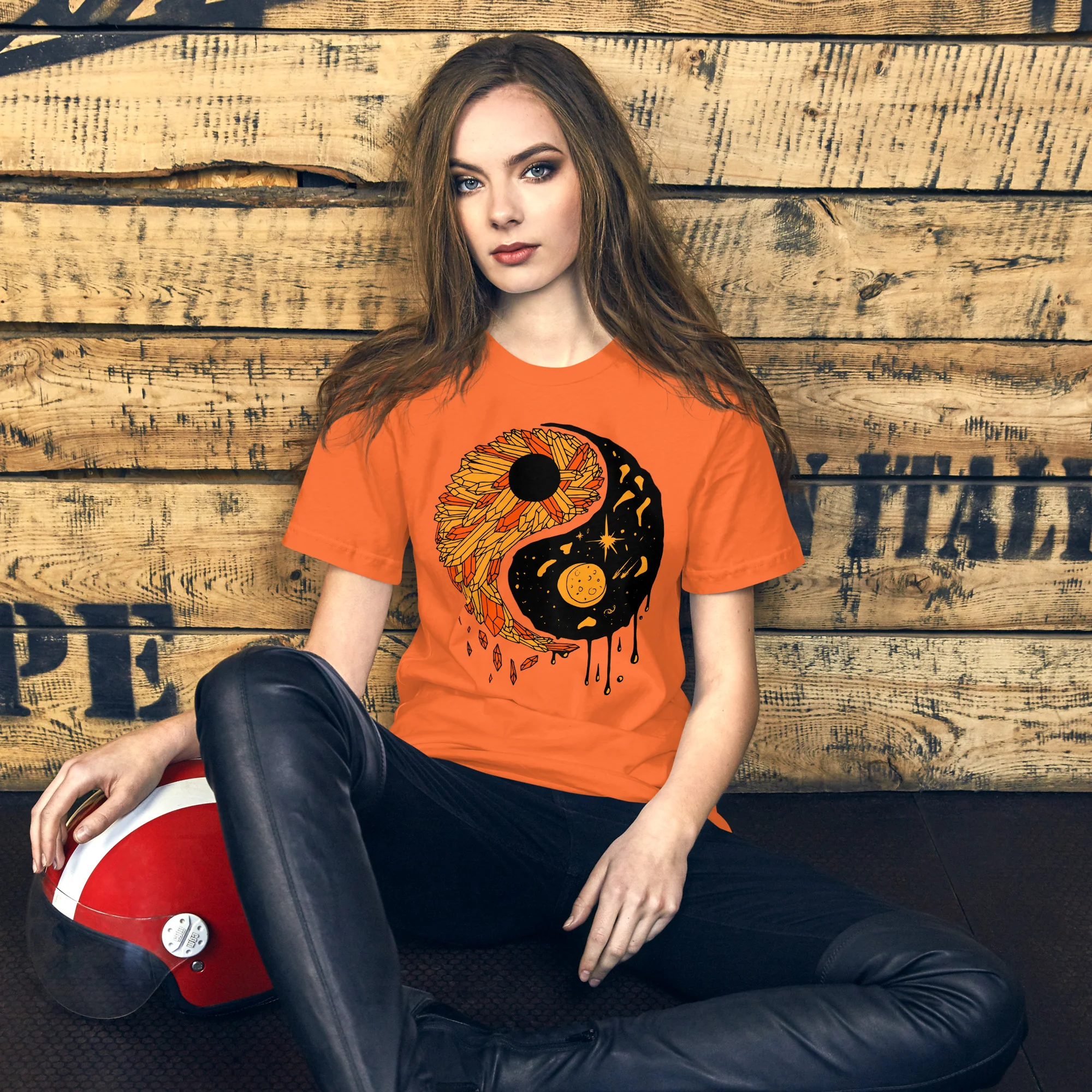 Woman wearing orange yin yang t-shirt with black graphic design featuring sunflower and moon motif
