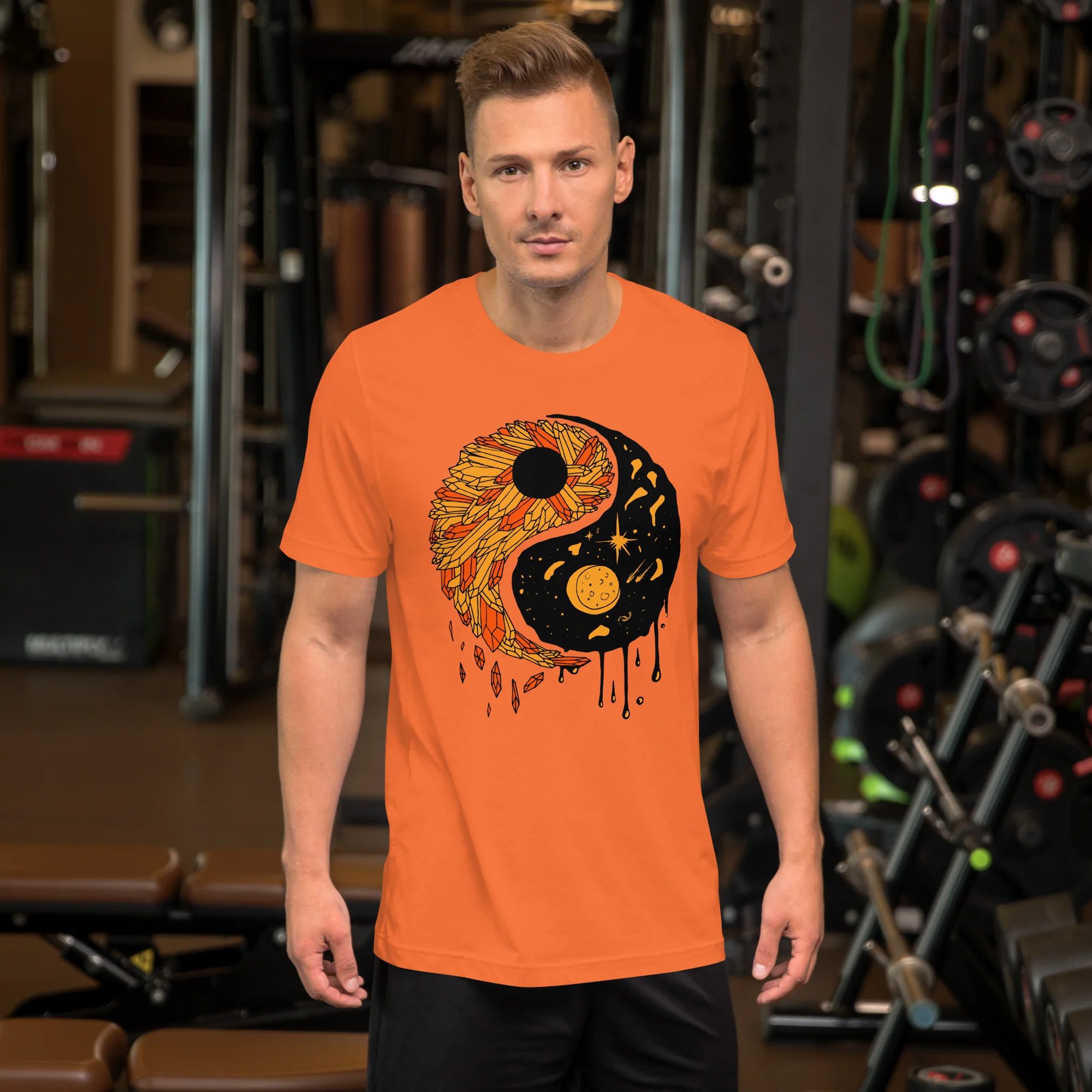 Man wearing orange yin yang t-shirt with sunflower and cosmic design in gym setting