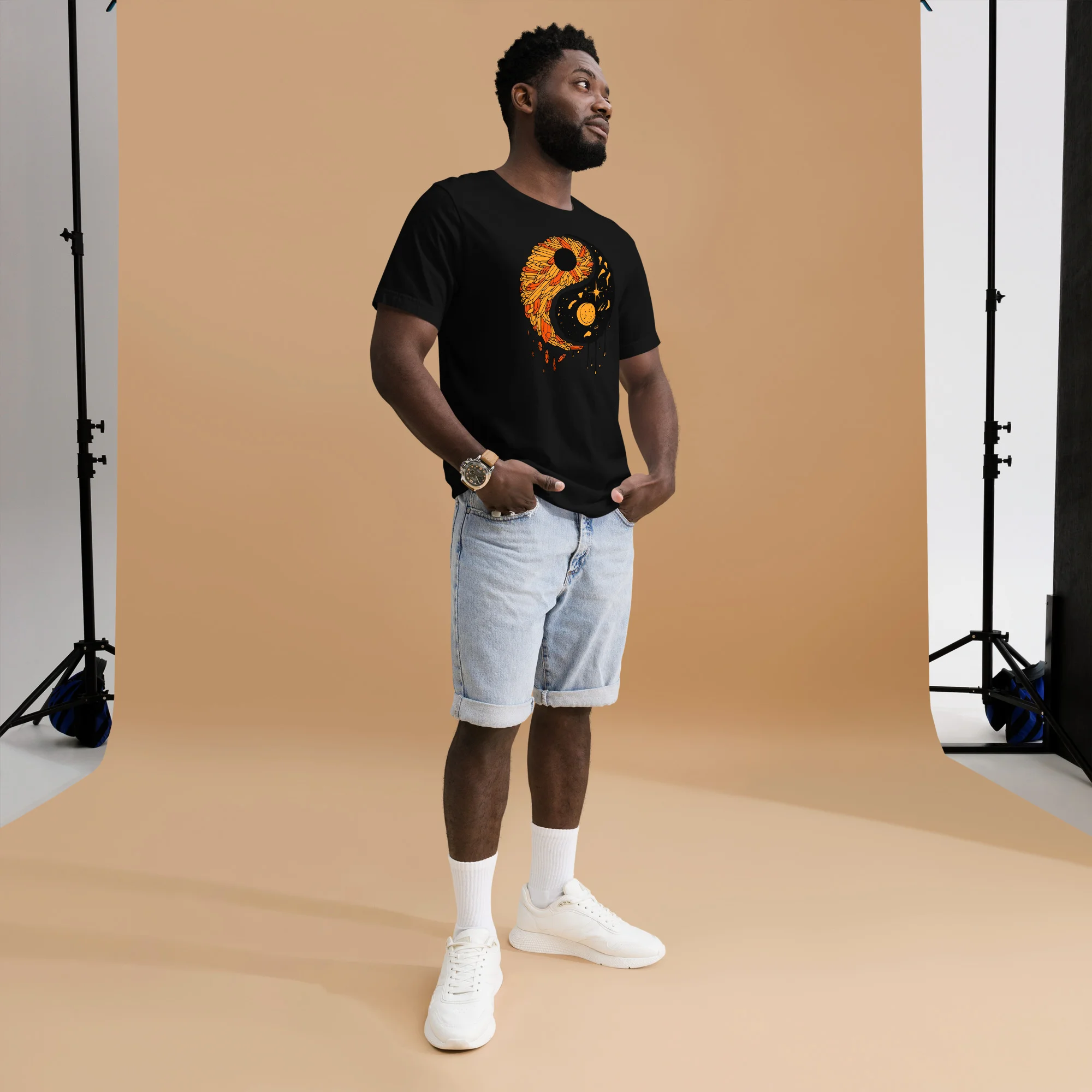Man wearing black yin yang t-shirt with orange graphic design, styled with light denim shorts